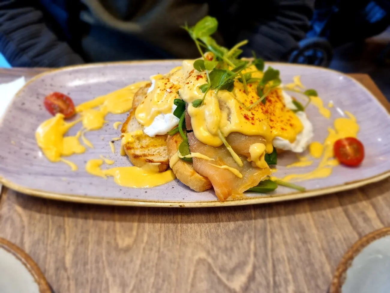Poached eggs and smoked fish on toast with hollandaise on a lilac plate.