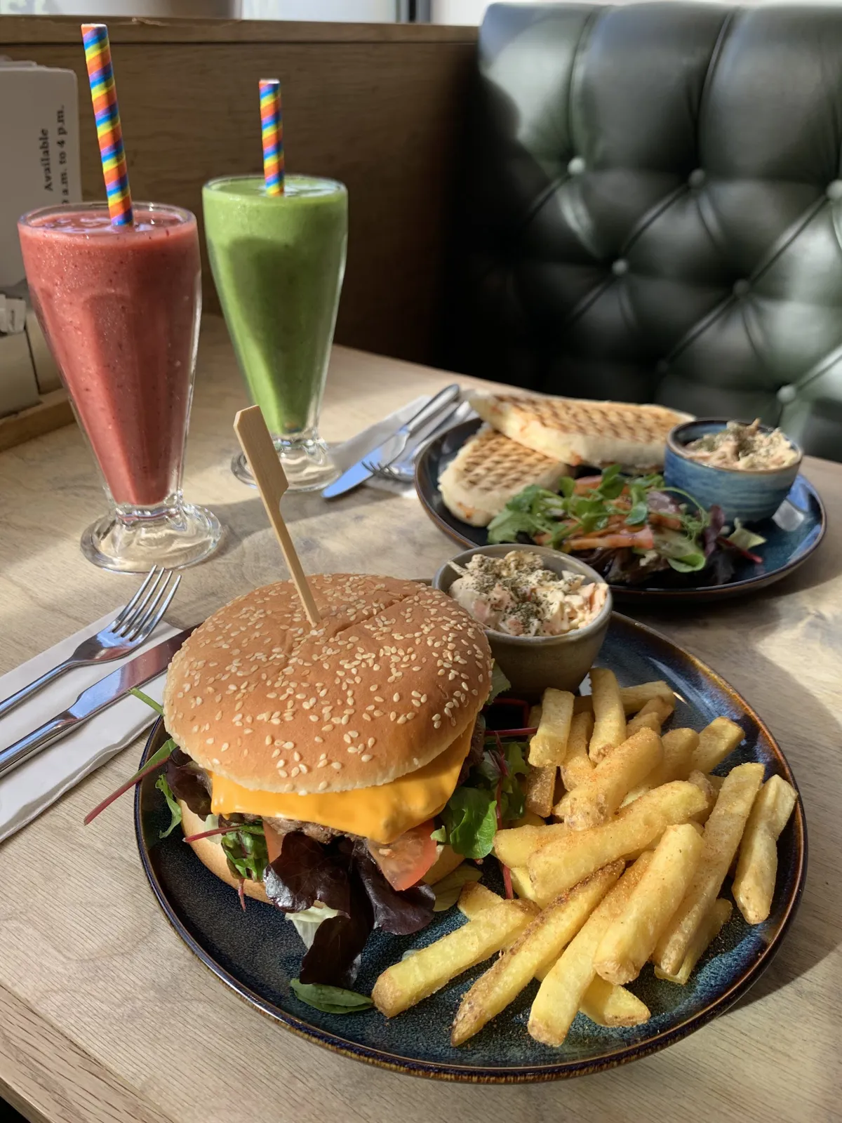 Table spread with burger, chips, smoothies and panini.